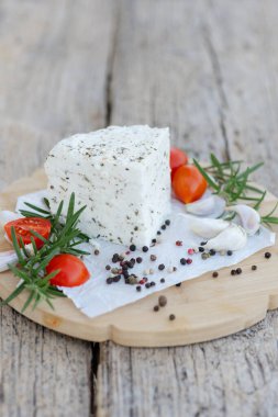 Tahta kesme tahtasının üzerinde servis edilen baharat ve otlarla tatlandırılmış taze peynir kamışı, davetkar bir aperatif veya aperatif oluşturur.