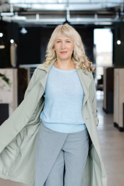 Kendine güveni olan bir kadın modern endüstriyel bir ofiste modern moda sergiliyor. Şık bir şehir ortamında zarafet ve özgüven yayar, profesyonelliği somutlaştırır..