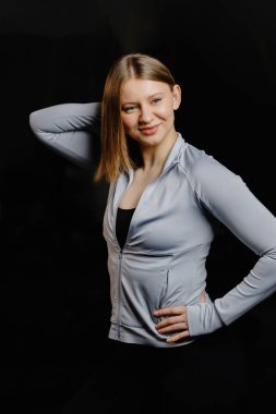 Spor giyim kuşağında formda bir kadın karanlık bir spor salonunda ısınıyor ve ısınıyor. Kararlılık ve enerji dolu yoğun bir antrenman için hazırlanıyor.