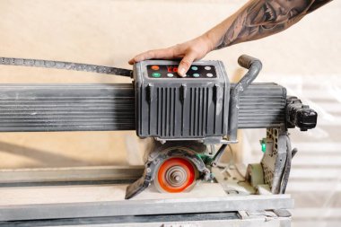 Profesyonel bir fayans kesme makinesi işleten inşaat işçisi, bir ev yenileme projesi için kesin kesintiler sağlıyor.