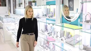 Cam ekranı gösteren bir mağazadan mücevher seçen bir kadın.