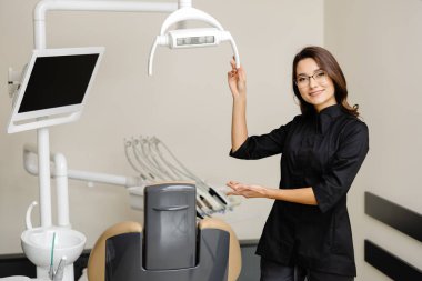 Modern klinikte genç bir dişçinin portresi. Bayan bir dişçi sizi nazikçe randevuya davet ediyor..