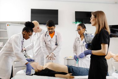 Çeşitli tıp öğrencileri bir eğitim mankeni üzerinde kardiyopulmoner canlandırma yapmayı öğreniyor.