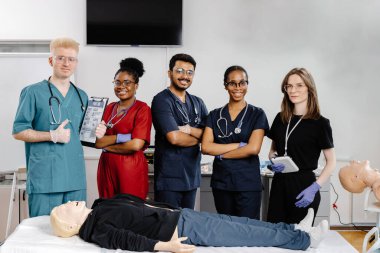 Bir grup çok ırklı tıp öğrencisi ilk yardım eğitimi sırasında mankenin üzerinde kardiyopulmoner canlandırma teknikleri öğreniyor.