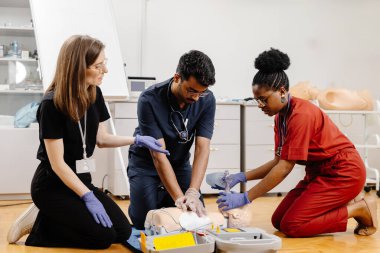 Çeşitli tıp öğrencileri hastane veya klinikte ilk yardım eğitimi sırasında tıbbi mankenler üzerinde kalp masajı yapıyor.