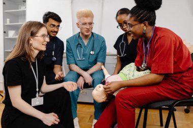 Çeşitli tıp öğrencileri eğitim sırasında tıbbi bir manikinle bebek bakımını öğreniyorlar.