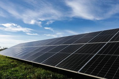 Güneş panelleri, mavi gökyüzü altında güneş ışığını emerek, yenilenebilir enerji ve sürdürülebilirliği sembolize ediyor.