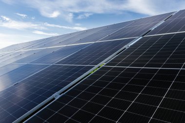 Güneş panelleri, mavi gökyüzü altında güneş ışığını emerek, yenilenebilir enerji ve sürdürülebilirliği sembolize ediyor.