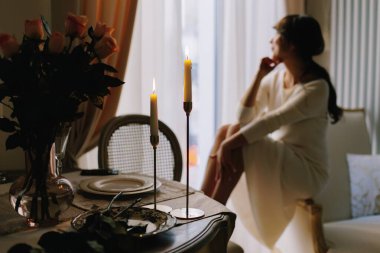 Woman sitting at a table with lit candles, contemplating during an intimate and elegant dinner setting