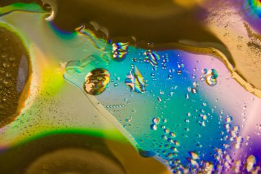 Renkli bir arkaplanda, makro fotoğraf çekiminde suya yağ damlaları.