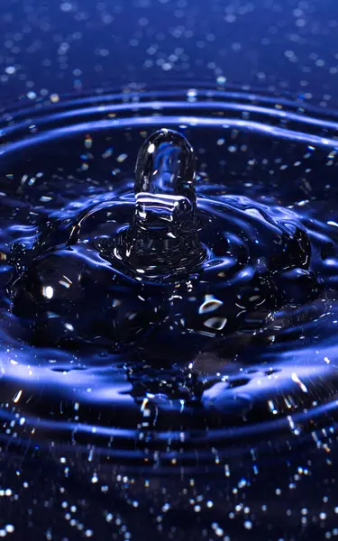 Su damlası - su yüzeyine renkli makro bir çekimle düşen bir damla