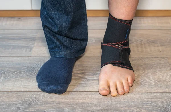 Orthopedic Ankle Brace on foot, wearing elastic ankle bandage wrap, selective focus
