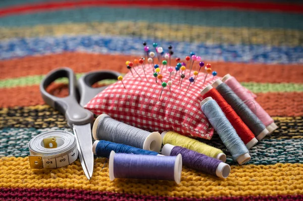 Sewing tools and accessories, spools of thread, scissor, pins and tape measure, selective focus