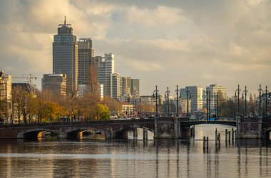 Ön planda Amstel nehri ve Omval Mahallesi 'ndeki modern yüksek binalarla Amsterdam' ın silueti.