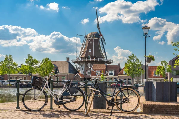 Güneşli bir bahar gününde Meppel şehrinde geleneksel yel değirmeni ve bisiklet sahnesi.