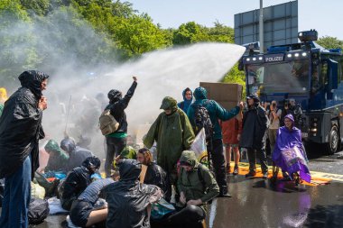 Lahey, Hollanda, 27.05.2023, Soykırım İsyanı eylemleri sırasında yolu kapatan iklim eylemcileri, su topu kullanan polis