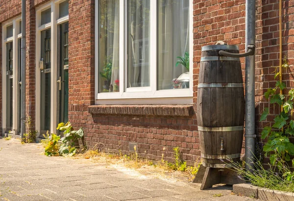 Wooden rain barrel for rainwater harvesting in the city street