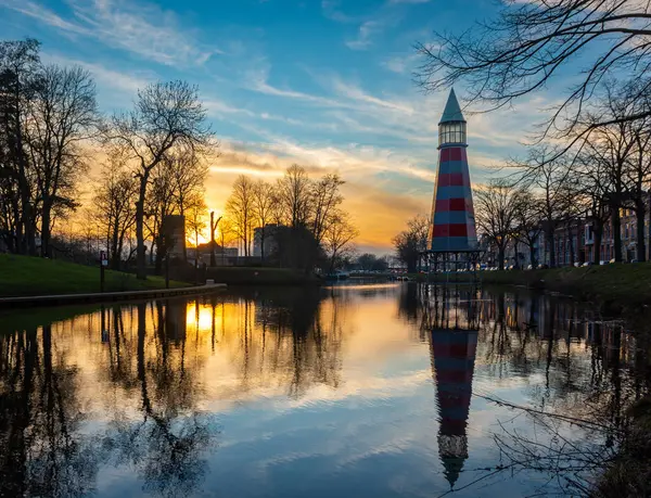 stock image Lighthouse by sunset in dutch city of Breda mirrored in the water surface