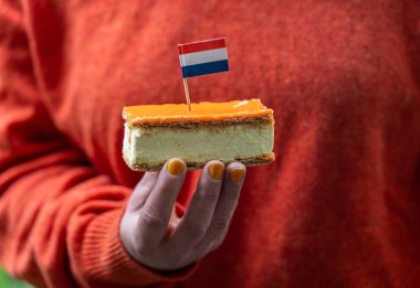 Turuncu Tompouce elinde, seçici odaklanma. Krallar Günü kutlamaları sırasında Hollanda 'da yenen popüler bir pasta.