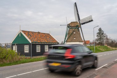 Geleneksel Hollanda yel değirmenini hızla geçiyor. Hollanda 'da seyahat ve trafik. Kasıtlı hareket bulanıklığı.