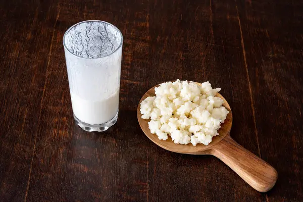 Kefir taneleri ve mayalanmış süt içeceği kırsal bir ahşap masada izole edilmiş.