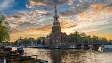 The Montelbaanstoren by sunset. Historical defense tower located on the bank of the Oudeschans canal in Amsterdam, The Netherlands clipart