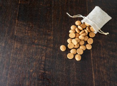 Tahta masanın üzerinde Kruidnoten olan küçük bir jüt çanta. Genellikle Aralık ayında Sinterklaas Şöleni 'nde yenen geleneksel Hollanda şekerlemeleri.