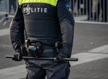 Rotterdam, Hollanda, 21.11.2024, Arkasından bir protesto mitinginde arkasında copu tutan Hollandalı polis memuru,