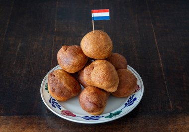 Flaman bayrağıyla süslenmiş tabakta geleneksel Hollanda olieboleni yığını