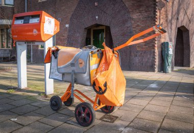 Amsterdam, Hollanda, 14.02.2025, PostNL dağıtım arabası ve turuncu çantalar. Posta, Hollanda postası, paket ve e-ticaret şirketi.