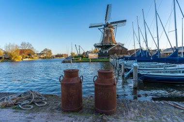 Friesland 'ın Woudsend kasabasında iki adet paslı süt kutusu ve tarihi yel değirmeni bulunan tipik Hollanda manzarası.
