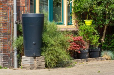 Plastik Yağmur Fıçısı Şehir Caddesindeki Downspout 'a Bağlandı, Yeniden Kullanım İçin Çevre dostu Yağmur Suyu Hasadı