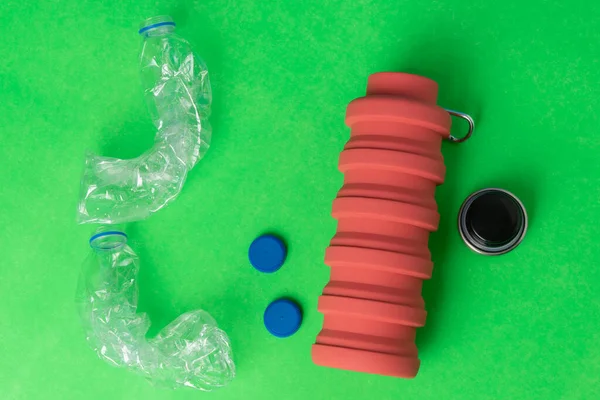 Plastic recycling and reuse concept on bright green background. Empty plastic bottles alongside a reusable water bottle. Environmental protection; waste recycling.