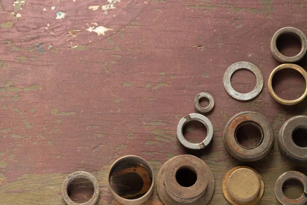 Small, circular industrial circles on a rustic, wooden background.  Washers, caps, rings, metal.