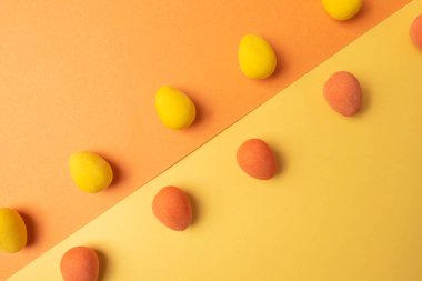 Zıt taraflarda sarı ve turuncu yumurta şekilli şekerlemelerin arkaplanı çapraz bir çizgi üzerinde renk yüzeyleri.