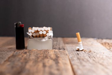 Sigara içmeyi bırakma kavramı. Açık bir paket sigara ve çakmak bir sigara ezilmiş ya da parçalanmış..