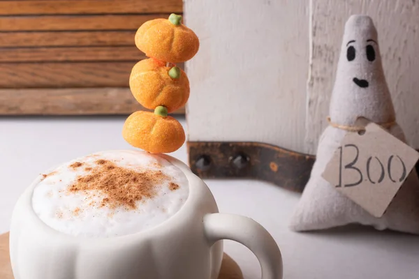 Pumpkin spiced coffee with a stack of tiny pumpkins.