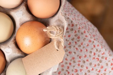 Kahverengi benekli, pembe ve yeşil aile yadigarı yumurtalar, yakın plan, masanın kenarındaki kağıt kutuda..