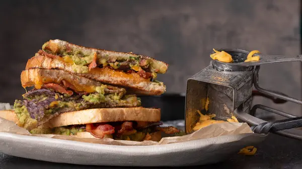 Bacon, guacamole, grilled cheese sandwich on sourdough bread.  National grilled cheese month