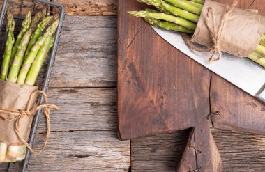 Ahşap zemin üzerinde taze yeşil kuşkonmaz dalları, üst görünüm.