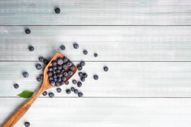 Taze, olgun böğürtlenler ahşap bir kepçeden kopyalanmış boşluklu ahşap bir masaya dökülüyor..