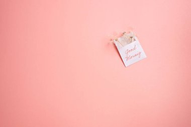 Günaydın, beyaz bir zarfın üzerinde küçük kurumuş çiçeklerle doldurulmuş pembe arka planda fotokopi alanı olan bir metin..