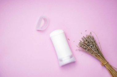 Beyaz deodorant kutusunda mor arka planda kurutulmuş lavanta çiçekleri var. Ürün modeli..