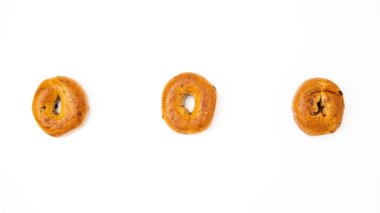 Beyaz arka planda üç tane tarçınlı kuru üzümlü simit..