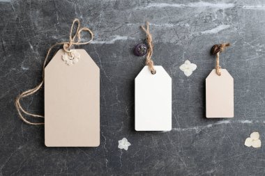 Üç boş hediye etiketi veya jüt sicim ve mermer bir yüzey üzerinde aksanlı etiketler.