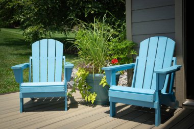 İki boş, turkuaz, güvertede mavi Adirondack sandalyeler, teras, rıhtım veya veranda içinde saksı bitkileri ve çiçekler var..
