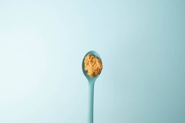 Mavi arka planda kıtır kıtır, kremalı fıstık ezmesi dolu mavi kaşık. Boşluğu kopyala.