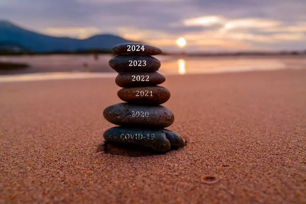 Happy new year 2024 is coming with great concept and design. Stone tower stacked on the beach