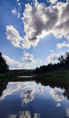 Yeşillik ve sudaki bulutların yansımasıyla güzel bir nehir.