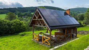 Yazın açık bir yaz gününde dağlarda güneş panelleri olan bir çardak.